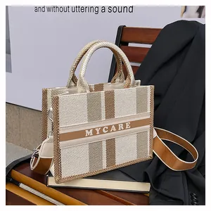 Vista dettagliata della borsa tote in tela a righe marroni e stampa MYCARE su sedia