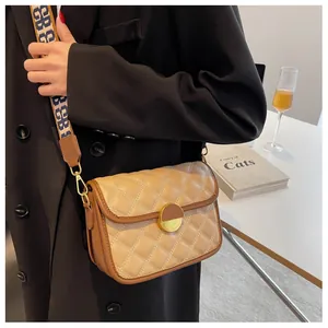 Detail of khaki quilted crossbody bag featuring a golden circular clasp and wide woven strap
