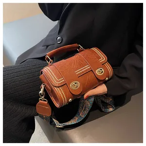 Detail of vintage brown textured leather handbag with gold twist locks and bohemian strap