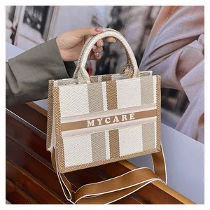 Dettaglio della borsa tote in tela a righe con tracolla larga in tessuto coordinata
