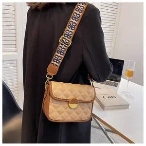 Detail of crossbody bag featuring beige quilted pattern and patterned wide shoulder strap