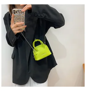 Vista macro della borsa a conchiglia verde neon con trama litchi e catena in argento