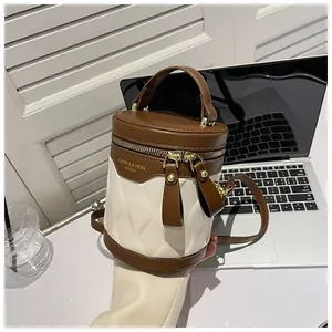 Detail of a chic two-tone cylinder bucket bag with gold zippers and brand lettering