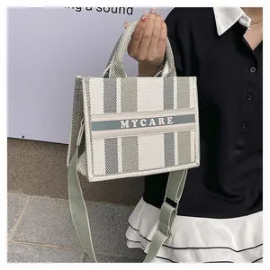 Dettaglio borsa shopper in tela a scacchi con tracolla verde e scritta MYCARE