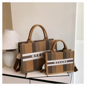 Dettaglio del set di borse tote in tela a righe con tracolla e scritte MYCARE decorative