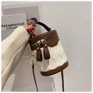 Detail of a brown and white cylinder bucket bag with textured waves and logo hardware