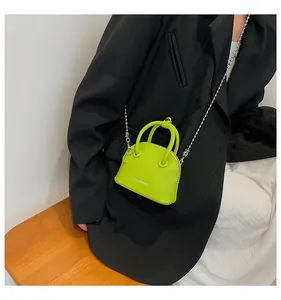 Dettaglio di una micro mini borsa verde neon con tracolla a catena e logo moda