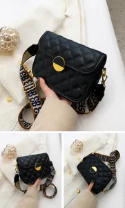 Detail view of black quilted crossbody bag with stylish wide patterned fabric strap