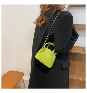 Mini borsa a conchiglia verde neon in pelle martellata con catena su blazer nero