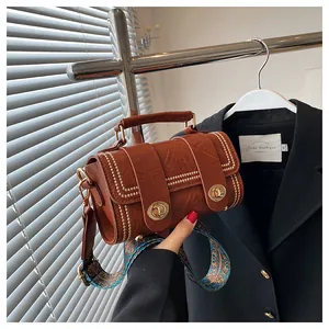 Macro view of vintage brown leather cylinder bag with gold studs and bohemian strap