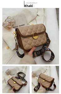 Close-up of khaki quilted crossbody bag with gold buckle and wide lettered strap