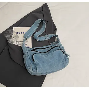 Detail view of denim messenger bag with adjustable strap and side drawstring texture