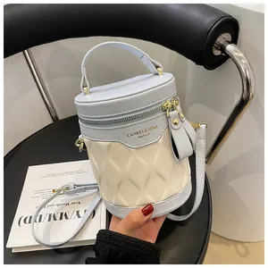 Close-up of a blue and beige bucket bag featuring a quilted pattern and gold zipper detail