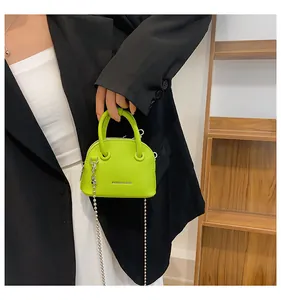 Mini borsa a conchiglia verde neon con trama litchi e catena in metallo su modella