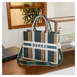 Dettaglio della borsa tote MYCARE in tela a righe su un elegante tavolo in legno