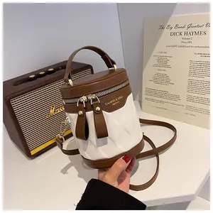 Detail of white and brown bucket bag with diamond texture and gold zipper hardware