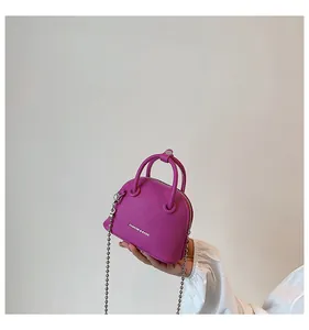 Dettaglio della mini borsa a conchiglia magenta con grana litchi e tracolla a catena