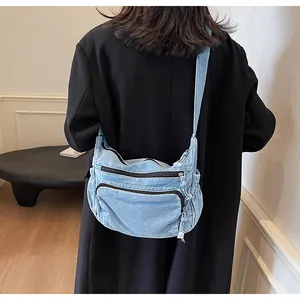 Detail of light blue denim messenger bag with double zipper pockets and washed texture