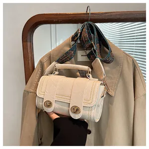 Detail of off-white crossbody bag with vintage crackle texture and patterned wide strap