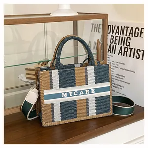 Dettaglio della borsa tote in tela con motivo a righe e tracolla regolabile rimovibile