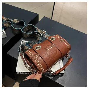 Detail of vintage brown cylinder bag with gold rivets and ethnic print wide strap