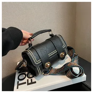 Detail of black cylinder handbag with gold rivets and bohemian patterned wide strap