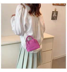 Vista posteriore di una modella con mini borsa a conchiglia fucsia con texture litchi e catena