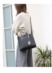Detail of black faux leather tote with crocodile texture and snakeskin pattern handles