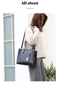 Detail of black tote bag with crocodile pattern and contrast snakeskin handles