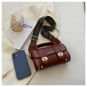 Macro shot of brown leather barrel bag with gold studs and ethnic woven strap details