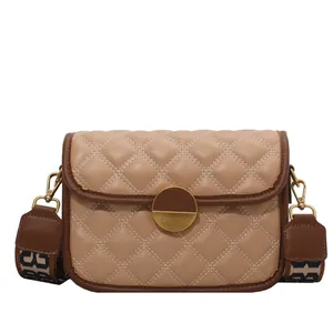 Elegant beige quilted crossbody bag with stylish wide patterned strap and metal clasp