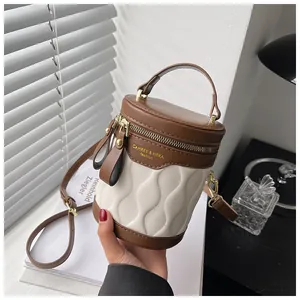 Detail of color-block bucket bag showing wavy texture and golden logo in hand