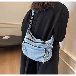 Detail of light blue denim messenger bag with zipper pockets and adjustable strap