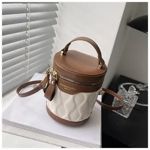 Detail of two-tone bucket bag featuring wave quilted leather and golden brand logo