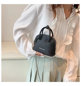 Dettaglio di una mini borsa a conchiglia nera con trama litchi e catena chic