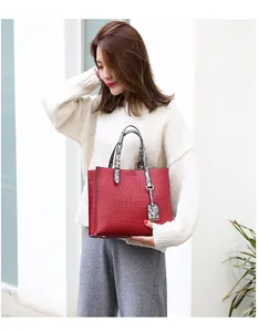 Detail of red crocodile textured tote bag with snakeskin pattern handle and tag