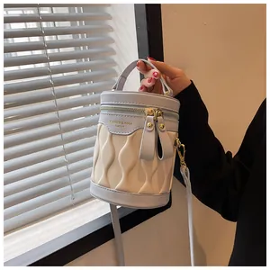 Detail of blue and beige pleated bucket bag with gold zipper and branded logo strap