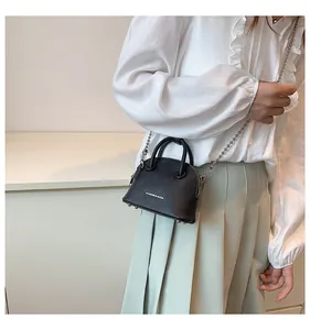 Mini borsa a conchiglia nera con texture litchi su modella e tracolla argentata