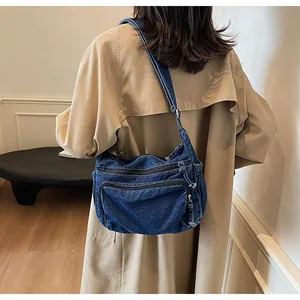 Detail view of the navy blue denim crossbody bag with dual zipper pockets and strap