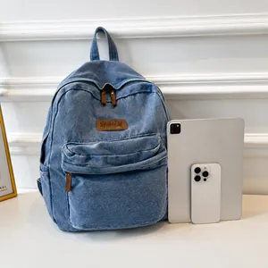Detail view of denim backpack with leather patch and tablet for size comparison