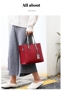 Detail of red crocodile textured tote bag with snakeskin pattern handles and metal feet