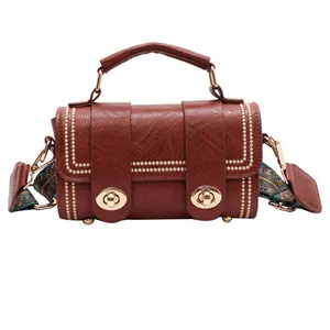 Brown vintage faux leather crossbody bag with dual turn-locks and ethnic printed strap