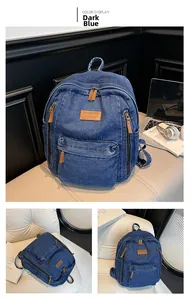 Detail of dark blue denim backpack with leather patches and multiple zippered pockets