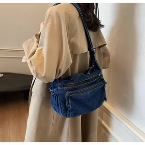 Detail of vintage denim messenger bag with multiple zipper pockets and side drawstrings