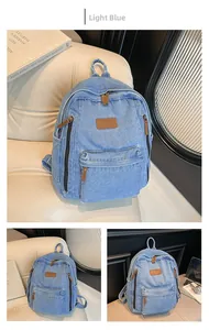 Detail of light blue denim backpack with brown leather logo patch and zip pockets
