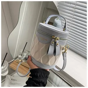 Detail of blue and cream bucket bag with wavy quilting and adjustable shoulder strap
