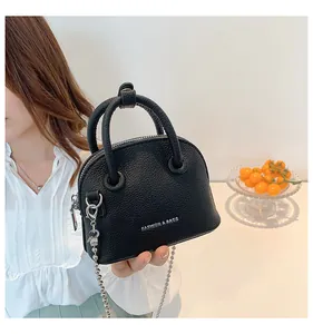 Dettaglio della borsa a conchiglia nera con texture litchi e tracolla a catena argento