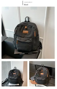Detail of black denim backpack with leather logo tag and multiple zipper compartments