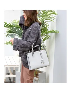 Detail of grey crocodile-textured tote bag with black and white snake-pattern handles