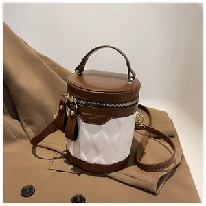 Detail of the white pleated cylinder bucket bag with brown leather accents and top handle